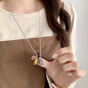 Detail of tiger eye stone pendant with silver bead cluster on a long dainty chain