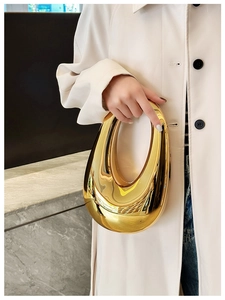 Polished gold oval clutch bag featuring a sleek reflective metallic finish and sculptural shape