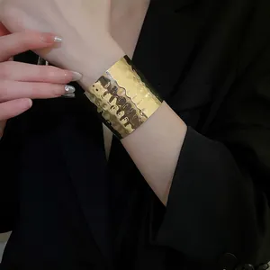 Irregular textured gold wide open cuff bracelet with hammered surface on female model