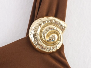 Detailed close-up of brown knit dress featuring gold shell-shaped decorative buttons