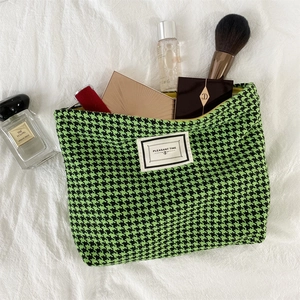 Detail of houndstooth toiletry bag showing spacious interior with lipstick and brushes
