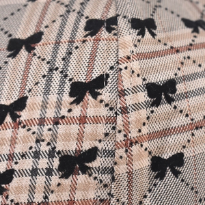 Macro detail of plaid fabric baseball cap with black bow print and diamond grid pattern