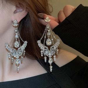 Close-up of sparkling silver tassel earrings with flower and teardrop rhinestone details