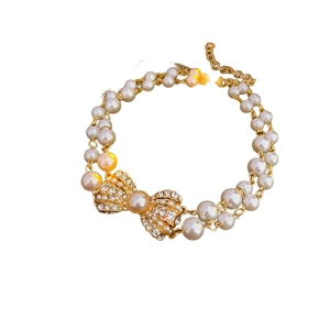 Double-layer white pearl bracelet with gold chain and sparkling rhinestone bow pendant