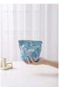 Detail of blue floral jacquard makeup bag with elegant embroidered flower patterns