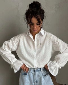 Detailed view of the textured polka dot fabric and elegant ruffled cuffs on white shirt