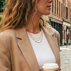 Detail of layered gold and black bead necklaces on a model in a stylish suit
