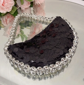Macro view of black sequin half-moon bag featuring large crystal rhinestone handle details