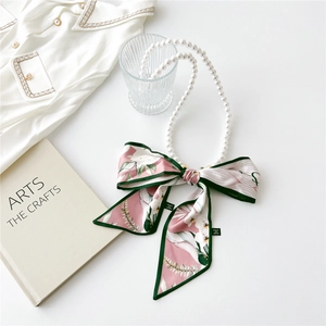 Detail of vintage pearl necklace with pink floral silk scarf on a clean white background