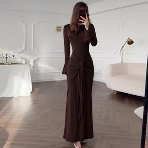Détail d'une robe longue marron à manches longues avec nœud à la taille et plis