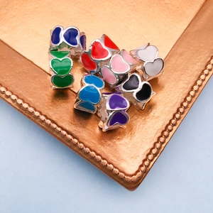 Macro shot of colorful enamel heart beads in a gold tray for DIY jewelry making