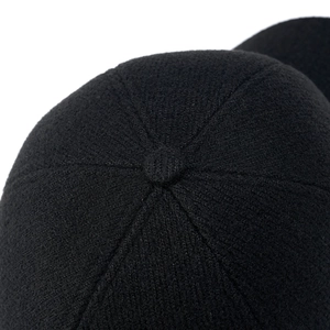 Macro shot of black winter baseball cap crown with knitted texture and top button
