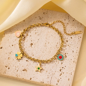 Detalle de pulsera de cadena dorada con dijes de esmalte y etiqueta K18 sobre piedra