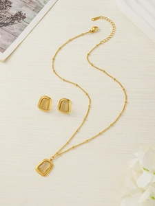 Close-up of golden necklace and earring set featuring elegant cat eye stone pendants