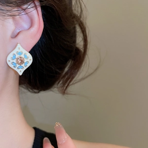Close-up of vintage white enamel diamond-set heart earring on model's ear