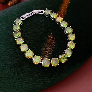 Macro detail of silver tennis bracelet with olive green round-cut cubic zirconia