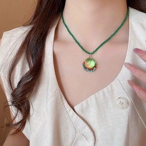 Detail of green crystal beaded necklace with geometric round resin pendant on model