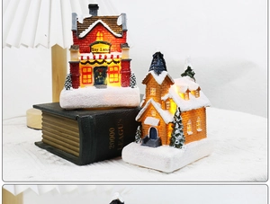 Detail view of glowing Christmas village houses with snowy roofs and LED lights