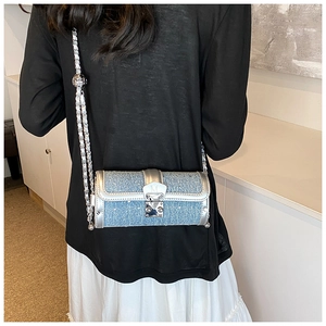 Detail of blue denim cylinder bag with rhinestones and silver chain on model