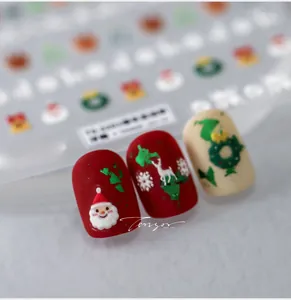 Détail macro de stickers ongles Noël 5D avec motifs Père Noël et rennes en relief
