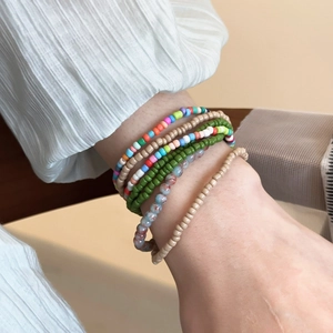Close-up of Bohemian layered seed bead bracelets with vibrant colors on woman's wrist