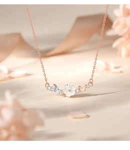 Macro shot of rose gold necklace featuring white shell flowers and a butterfly pendant