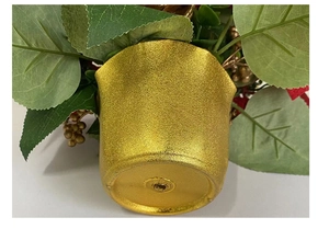 Detail of golden frosted artificial plant pot with green leaves and berry ornaments