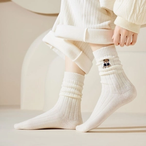 Detail of cream white ribbed knit socks featuring a cute bear embroidery accent