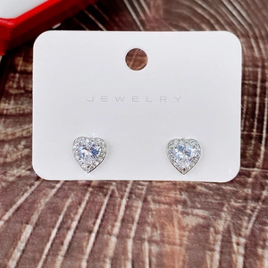 Macro detail of heart-shaped zircon earrings with a halo setting on a jewelry card