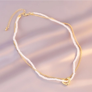 Elegant double-layered gold necklace with white pearls and a polished heart pendant