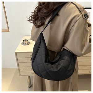 Close-up of black quilted diamond pattern on minimalist large capacity crossbody bag