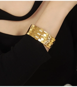 Close-up of a wide 18K gold-plated chain bracelet with wing-shaped zircon accents on a wrist