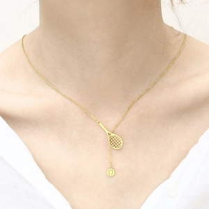 Detailed close-up of a gold-finish tennis racket and ball pendant necklace on a model