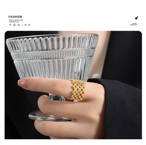 Detail of gold hollow grid ring with sparkling Czech crystals on woman holding glass