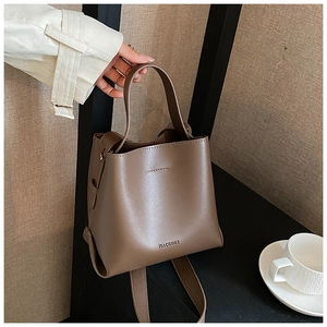 Close-up of a brown leather bucket bag hanging on a black stand with a minimal aesthetic