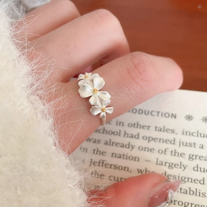 Close-up of matte silver triple flower ring with gold stamens worn on fingers