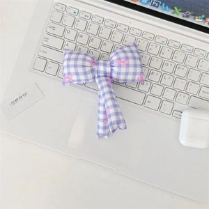 Detail of lavender checkered fabric hair bow with pink accents on a white keyboard