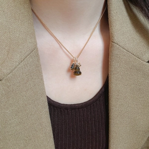 Detail of tiger eye stone gourd pendant necklace on model with golden chain