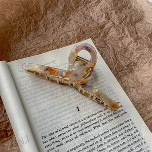 Macro view of tortoiseshell acetate hair claw with gold metal clip on vintage book page
