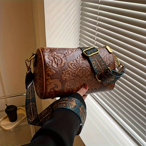 Detailed close-up of vintage embossed floral patterns and wide ethnic style strap on a bag