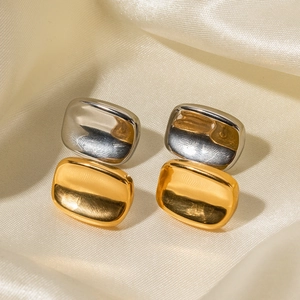 Polished 18k gold and silver two-tone rectangular stud earrings on silk background