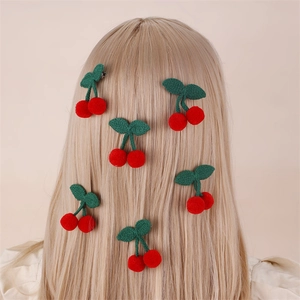 Cute red cherry hair clips for girls featuring plush fruits and green leaves on blonde hair
