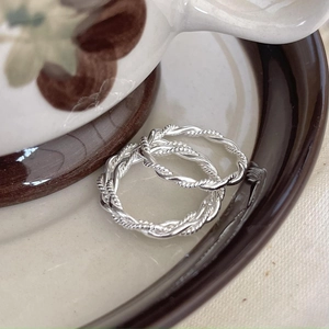 Detail shot of two twisted rope stackable 925 silver rings on a vintage ceramic tray