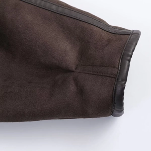 Detail of dark brown faux suede jacket sleeve showing leather trim and precise stitching