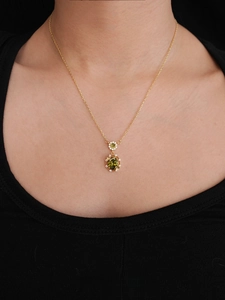 Detailed view of 18K gold-plated necklace with oval green zircon pendant on model