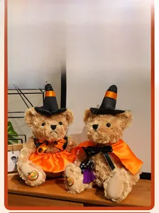 Detail of plush Halloween teddy bears in witch hats and pumpkin outfits on wooden surface