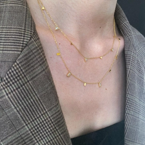 Double-layered golden titanium steel necklace with sparkling geometric pendants on a model