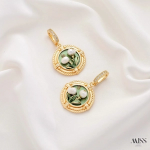 Detail of vintage round enamel pendants with white pearls on white silk background
