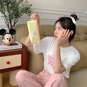 Close-up of yellow canvas pencil pouch held by hand in a cozy domestic living room