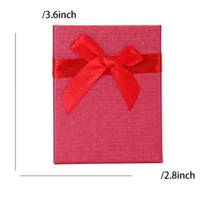 Top view of red textured gift box with ribbon bow measuring 9.1cm by 7.1cm